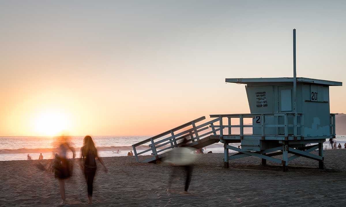 08.31.2019-Featured-Image Sunset on the beach, with a lifeguard stand in silhouette. It's here that I remember my friend on International Overdose Awareness Day.